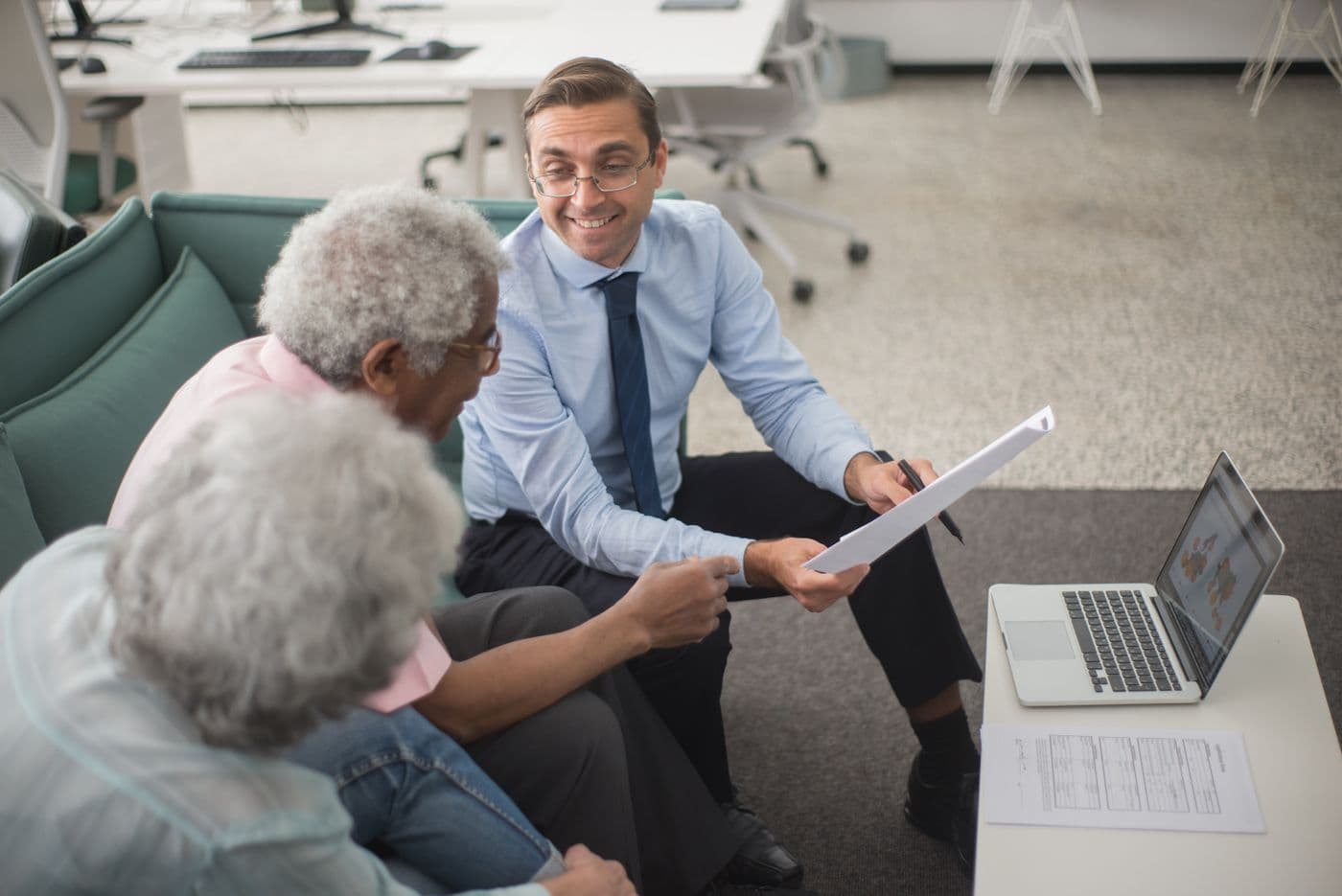 An advisor smiling as he walks an older couple through a document in his office