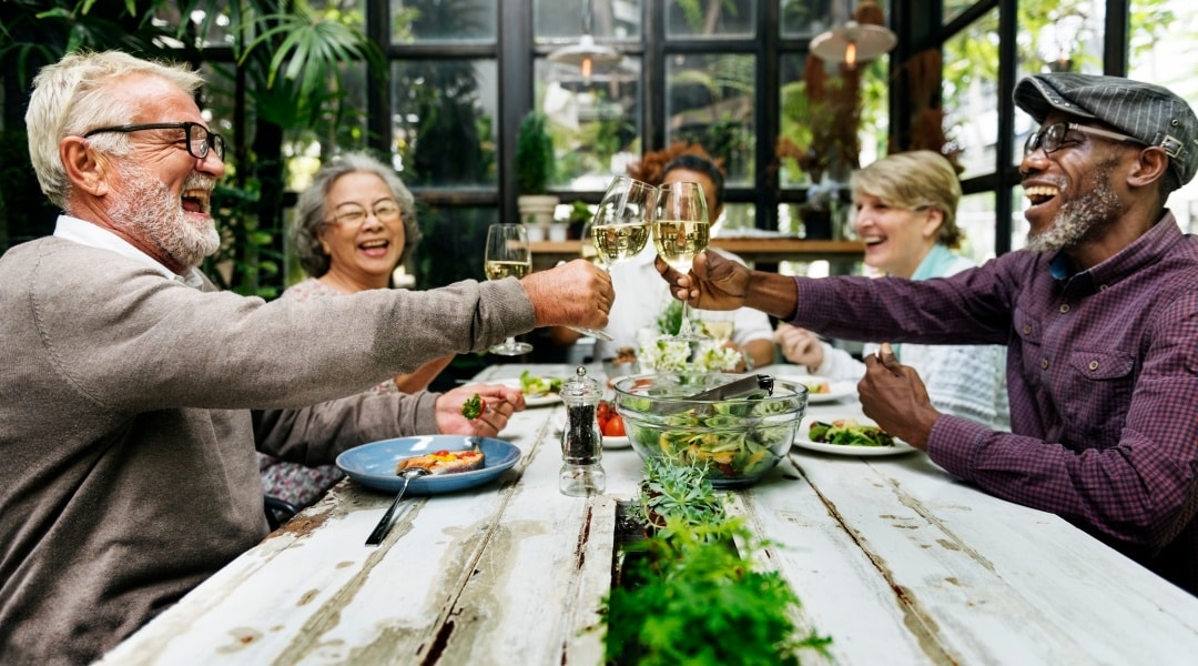 Diverse group of middle-aged people celebrating around a table, representing use of a Guaranteed Lifetime Income Annuity